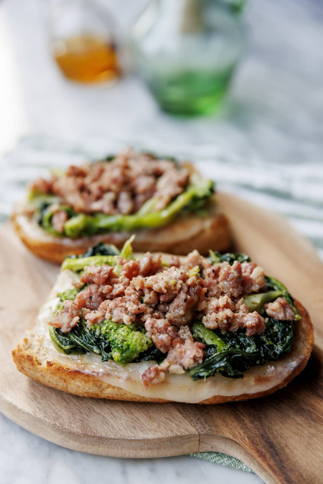 Toasted bread slices topped with cooked greens and crumbled sausage.