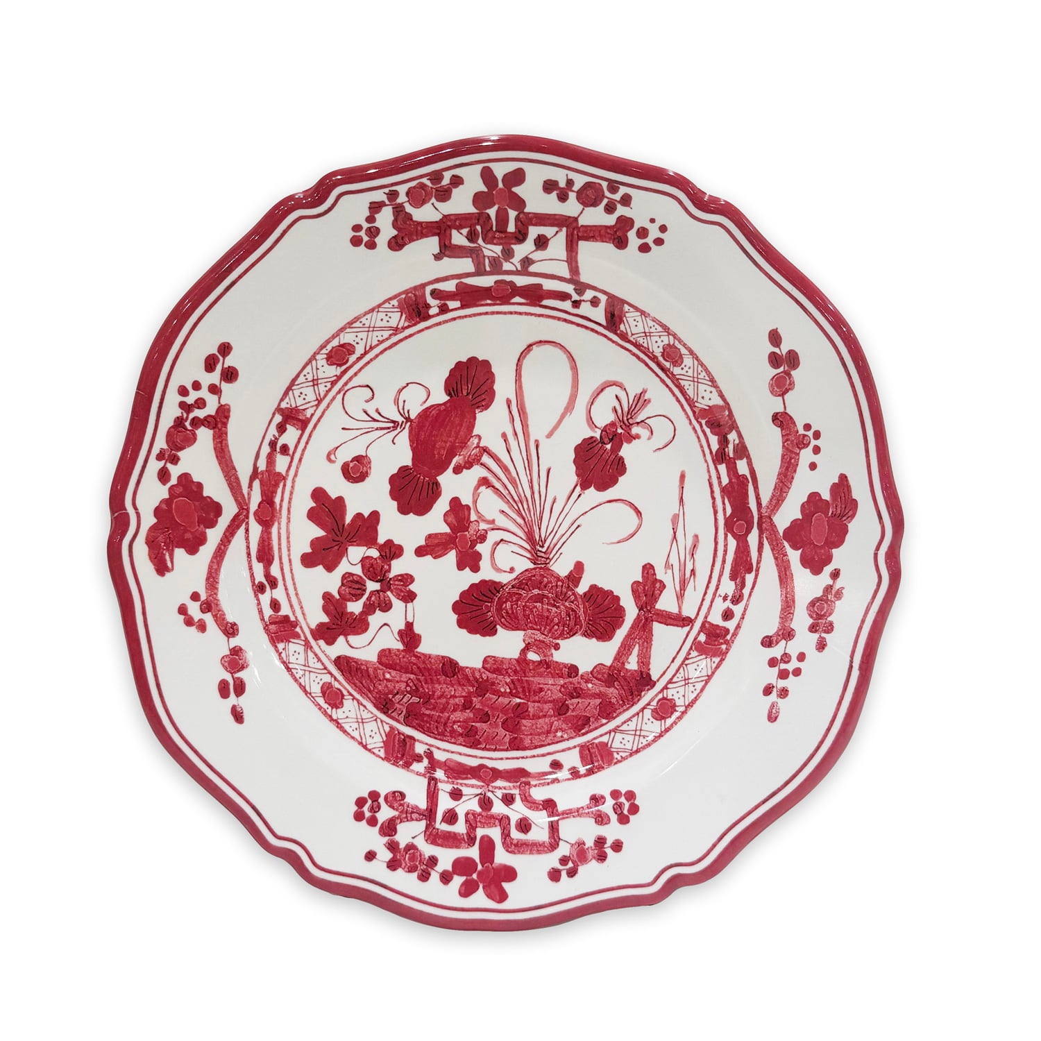 White ceramic plate with scalloped edges, featuring a red floral and botanical design in the center and along the border.