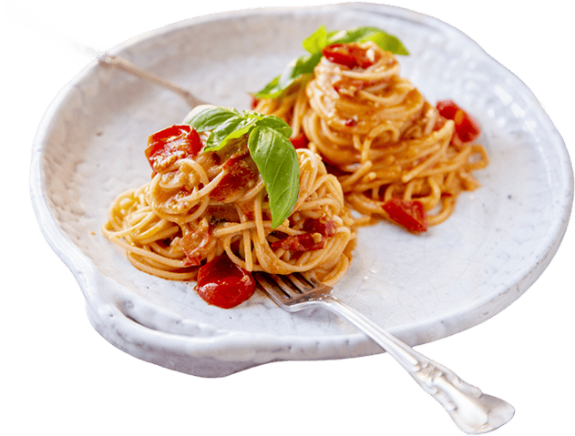 A white plate with two small servings of spaghetti, cherry tomatoes, and basil, with a silver fork resting on the plate.